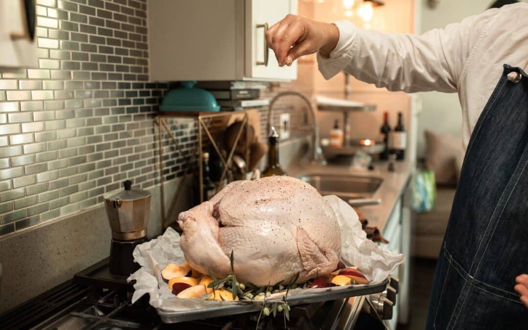 Crested Butte Real Estate - Chef preparing a Turkey in the kitchen. Sprinkling seasonings over turkey.