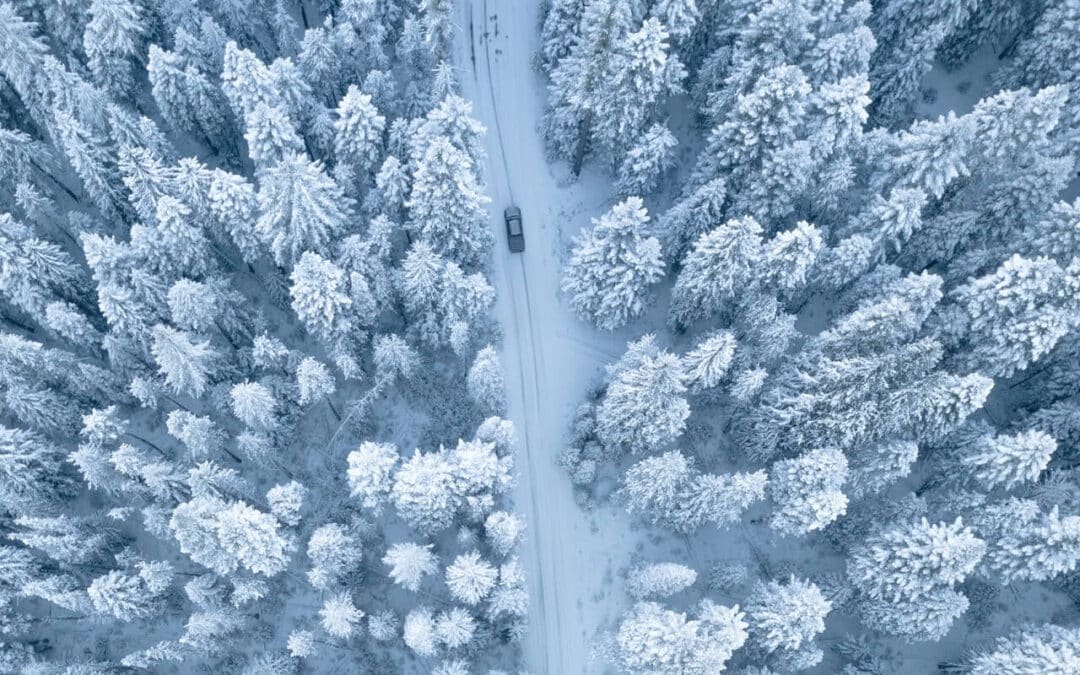 Crested Butte Real Estate - Aerial view of vehicle on a winter road through the forest.