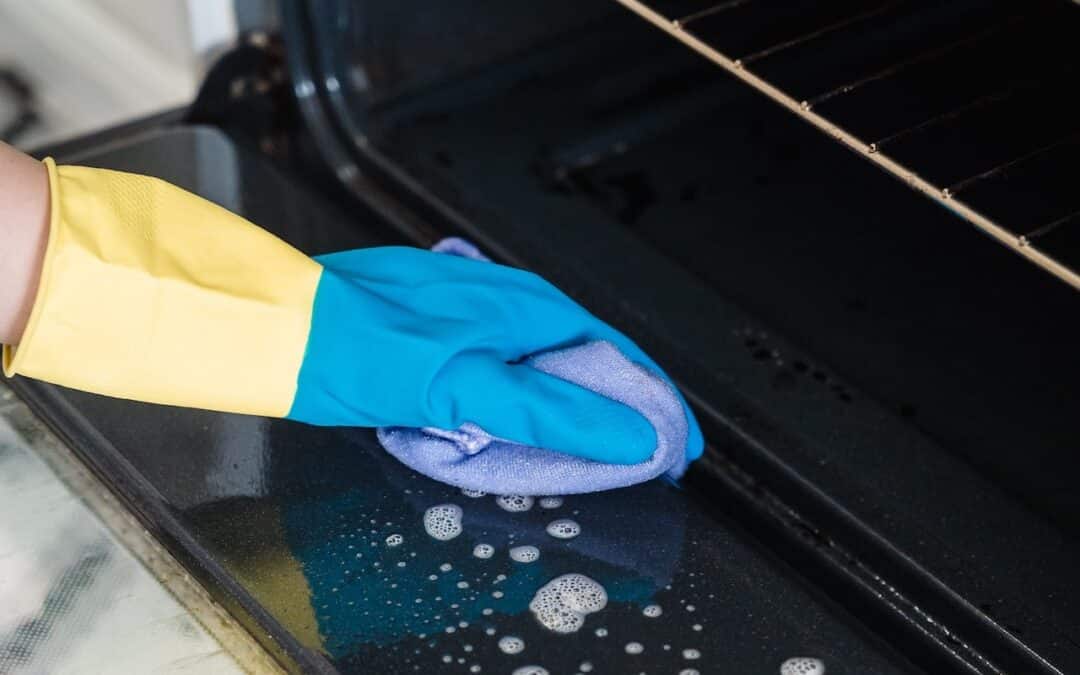 Crested Butte Real Estate - Spring Cleaning Tips - person wearing rubber gloves cleaning the oven.