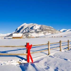 View of a split rail fence with a holiday bow decoration, Crested Butte, Colorado, Rocky Mountains, Winter