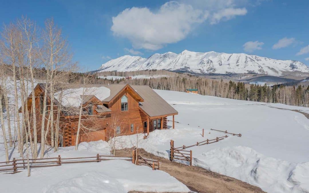 Crested Butte real estate agent Kiley Flint has listed 45 Osage Trail, Gunnison. This is an aerial exterior image of the 2 story log cabin with the Anthracite mountains in the distance.